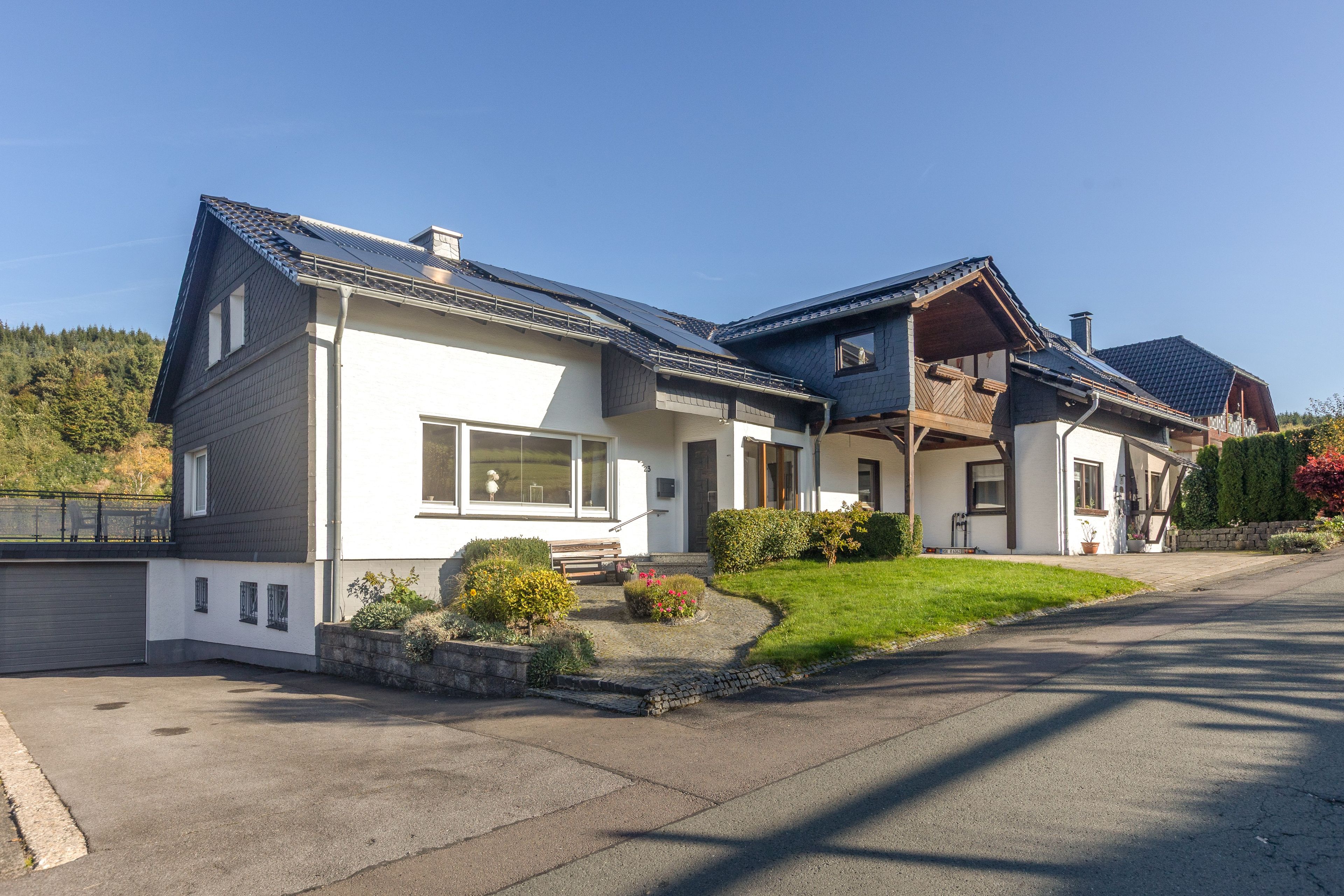 A two-story house with a sloped roof, large windows, and a well-maintained lawn.