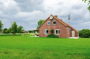 Ein eingeschossiges Backsteinhaus mit Satteldach, Satellitenschüssel und kleiner Veranda.