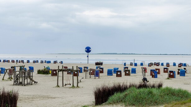 A beach with numerous beach huts and a large blue sign. - Holiday Home 'Ferienhaus Lüttje Dörp' with Private Terrace, Private Garden and Wi-Fi (Blomberg)