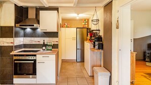 A modern kitchen with a built-in oven, a stainless steel range hood, and a refrigerator. - Holiday Home 'Ferienhaus Lüttje Dörp' with Private Terrace, Private Garden and Wi-Fi (Blomberg)