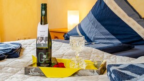 A bed with a bottle of wine, a glass, and a tray with a rose. - Holiday Home 'Ferienhaus Lüttje Dörp' with Private Terrace, Private Garden and Wi-Fi (Blomberg)