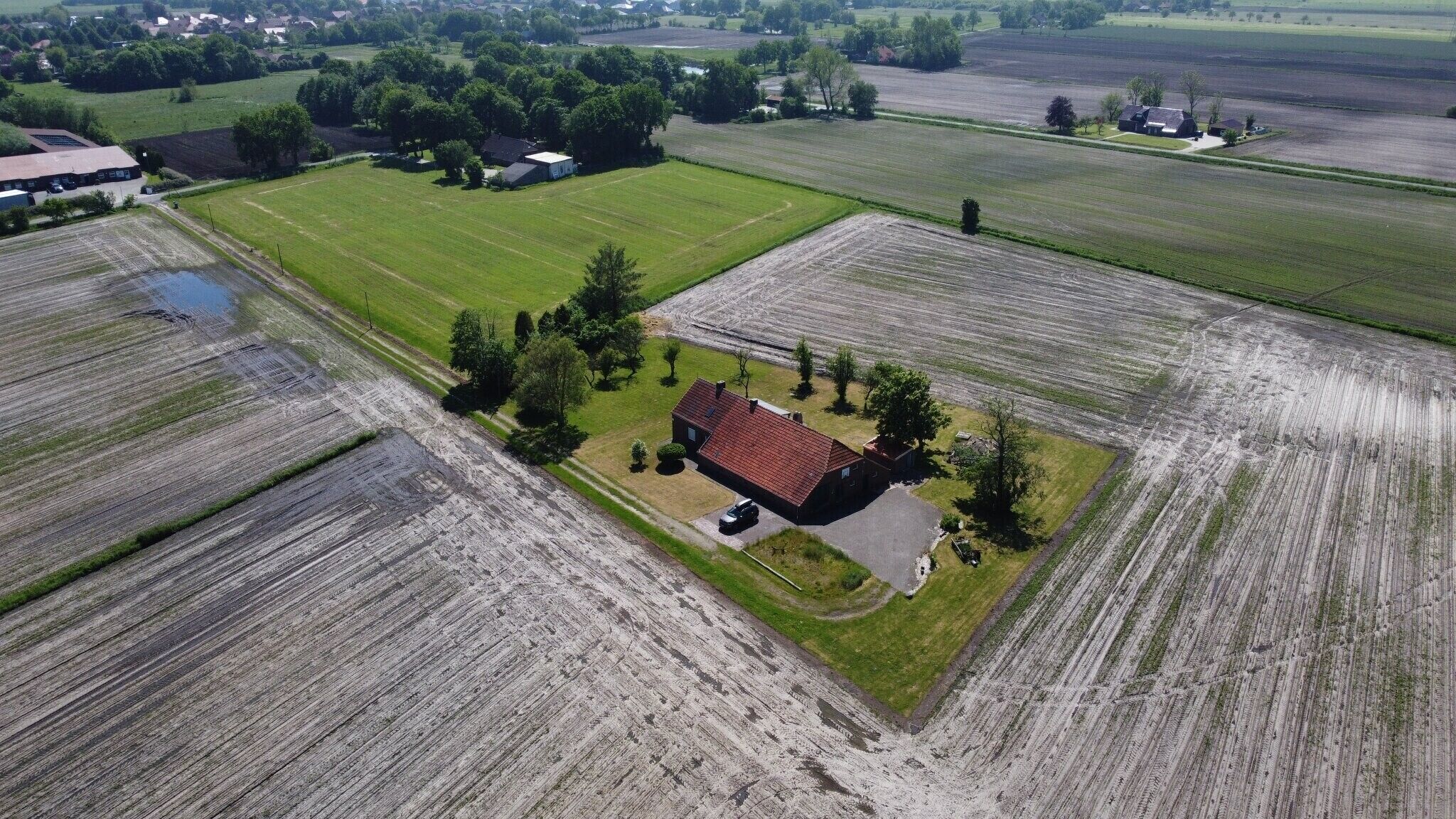 An aerial view of a rural property with fields, a house, and a small pond.