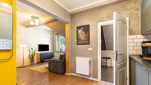 Una cocina moderna con horno empotrado, un comedor con mesa y sillas, y una sala de estar con sofá y televisor.