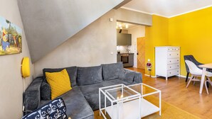 Una sala de estar moderna con un sofá seccional gris, una mesa de centro de vidrio y un comedor con una mesa y sillas blancas.
