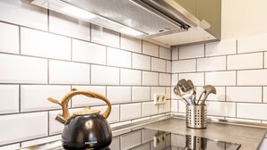 Una cocina moderna con baldosas blancas estilo metro, una cocina por inducción negra y una tetera.
