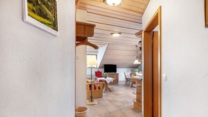 A hallway leading to a dining area with wooden furniture, a television, and a red flower vase. - Holiday Apartment 'Type B, 50sqm' with Mountain View, Private Terrace and Wi-Fi (Feldberg (Schwarzwald))