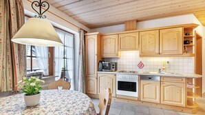 A kitchen with wooden cabinets, a microwave, stove, and a sink. - Holiday Apartment 'Type B, 50sqm' with Mountain View, Private Terrace and Wi-Fi (Feldberg (Schwarzwald))
