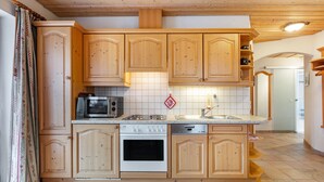 A kitchen with wooden cabinets, a microwave, stove, and dishwasher. - Holiday Apartment 'Type B, 50sqm' with Mountain View, Private Terrace and Wi-Fi (Feldberg (Schwarzwald))