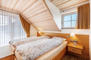 A bedroom with two beds, a window, wooden ceiling, and bedside lamps. - Holiday Apartment 'Type B1, 50sqm' with Mountain View, Shared Terrace and Wi-Fi (Feldberg (Schwarzwald))