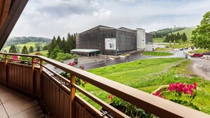 A modern building with a large parking area and a view of a green landscape. - Holiday Apartment 'Type B1, 50sqm' with Mountain View, Shared Terrace and Wi-Fi (Feldberg (Schwarzwald))