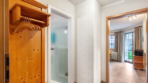 A hallway with a wooden door, a glass door, and a view into a room with a television and curtains. - Holiday Apartment 'Type B Apartment 2' with Mountain View, Shared Terrace and Wi-Fi (Feldberg (Schwarzwald))