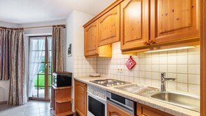 A kitchen with wooden cabinets, a microwave, oven, and dishwasher. - Holiday Apartment 'Type B Apartment 2' with Mountain View, Shared Terrace and Wi-Fi (Feldberg (Schwarzwald))
