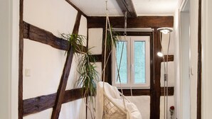A room with exposed wooden beams, a hanging chair, a potted plant, and a door with a window. - 'Im Gässla' Holiday Apartment with Wi-Fi (Spalt)