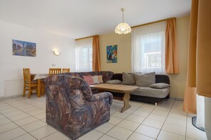 Un salon avec un canapé, une table à manger et des chaises, et un tableau accroché au mur.