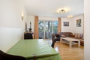 A room with a bed, a desk, a chair, a sofa, and a balcony with a view.