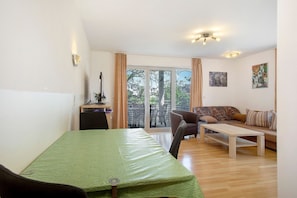 A room with a bed, a desk, a chair, a sofa, and a balcony with a view.