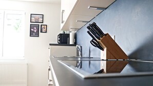 A modern kitchen with a black countertop, a microwave, and a knife block. - Holiday Home 'Hq16 - Modern' with Private Terrace, Balcony and Wi-Fi (Neuenburg am Rhein)