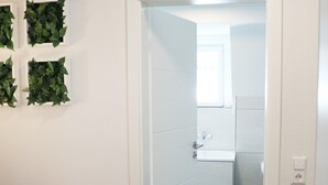 A hallway with a wooden floor, white walls, and a door leading to a bathroom with a window. - Holiday Home 'Hq16 - Modern' with Private Terrace, Balcony and Wi-Fi (Neuenburg am Rhein)