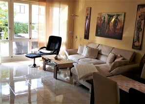 A living room with a sofa, a chair, a coffee table, and artwork on the walls. - Apartment 'Laura' with Private Terrace, Private Garden and Wi-Fi (Langenargen)