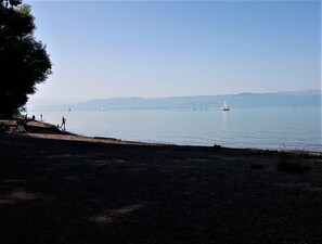 A beach with a clear view of the water and distant mountains. - Apartment 'Laura' with Private Terrace, Private Garden and Wi-Fi (Langenargen)
