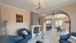 A living room with a fireplace, a dining area, and a kitchen visible through an archway. - 1st floor apartment4 kilometers from beziers with secure parking (Béziers)