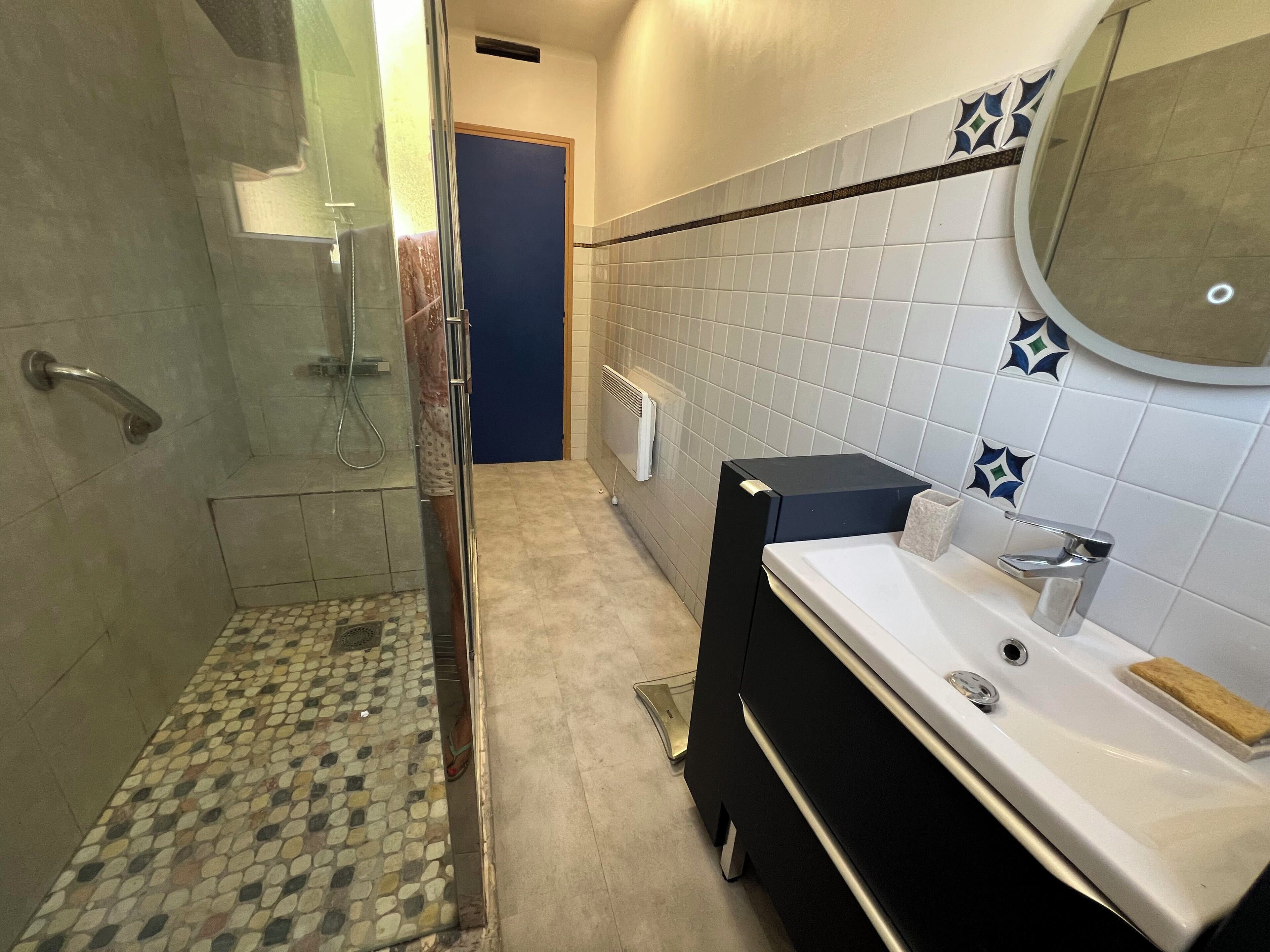 Un baño con ducha, lavabo, espejo e inodoro.