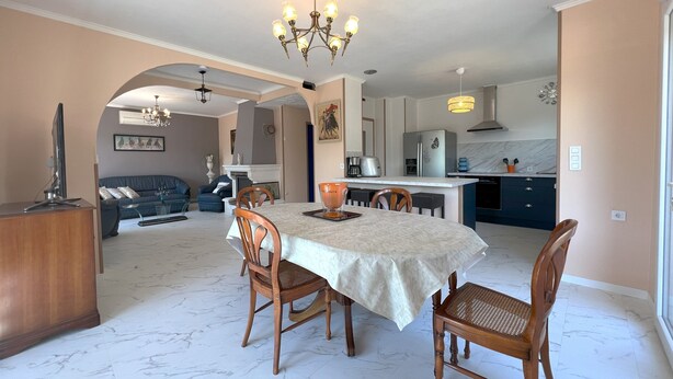 A spacious living area with a dining table, chairs, and a kitchen in the background. - 1st floor apartment4 kilometers from beziers with secure parking (Béziers)