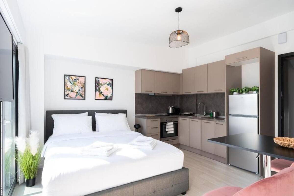 Een moderne slaapkamer met een groot bed, een kleine kitchenette en een eethoek.