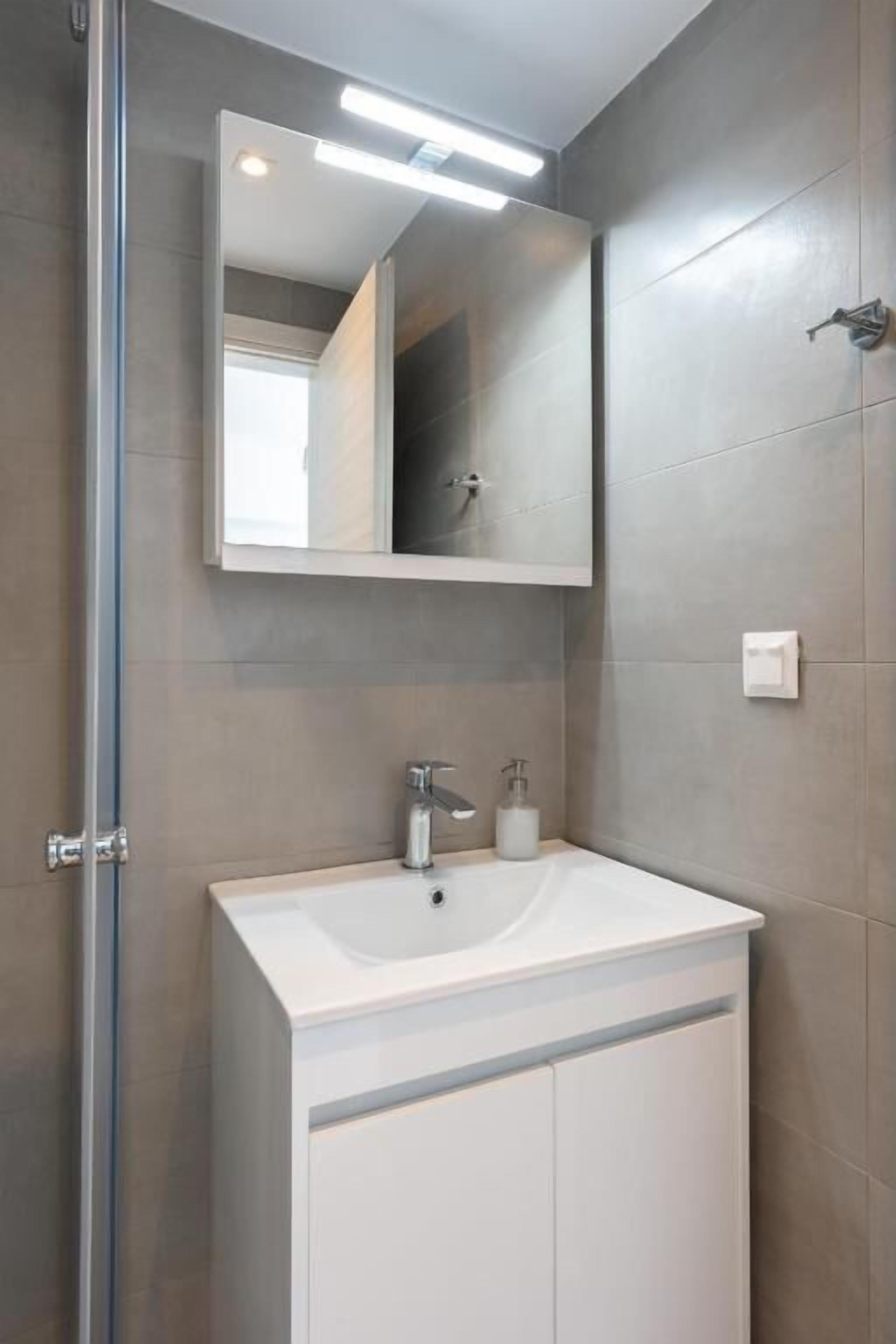 A bathroom with a white sink, a mirror, and a shower.
