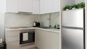 Una cocina moderna con armarios blancos, un refrigerador de acero inoxidable, un horno empotrado y un salpicadero de mármol.