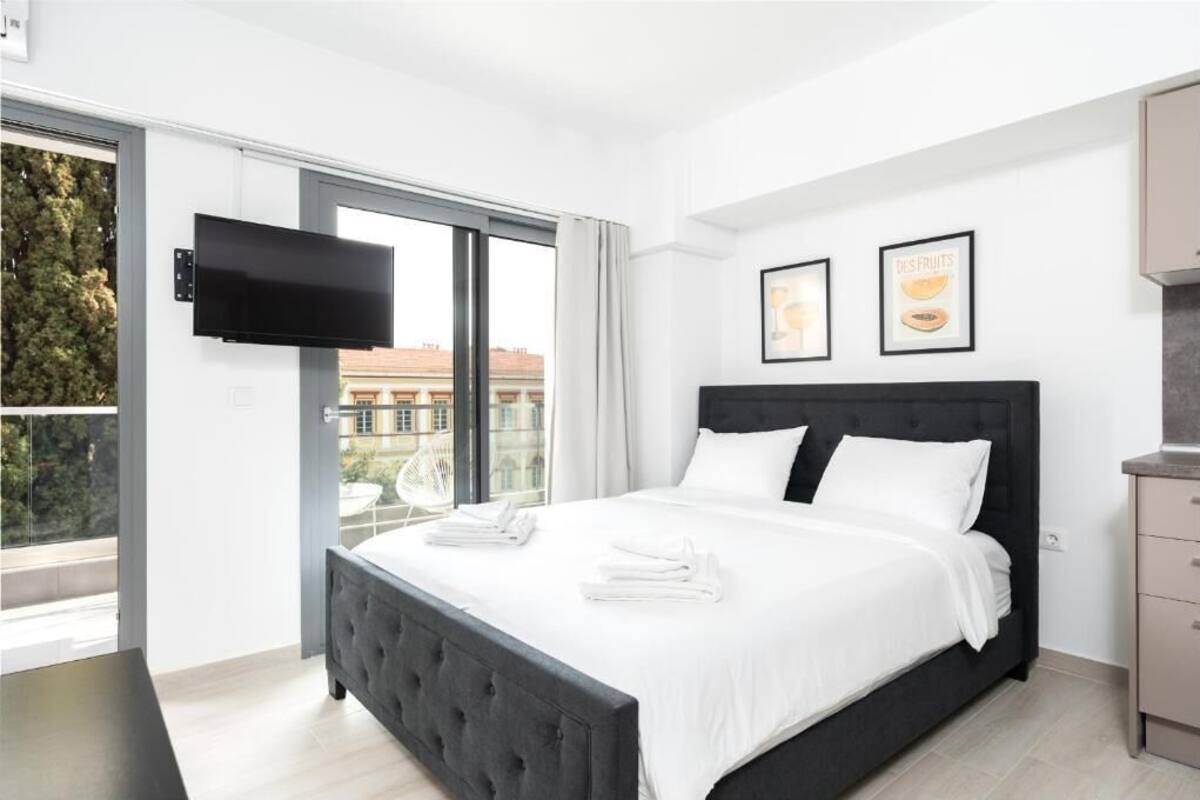 Een moderne slaapkamer met een groot bed, een flatscreen televisie aan de muur en uitzicht over de stad.