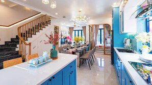 Una cocina moderna con armarios azules, una isla central y un comedor con candelabro.