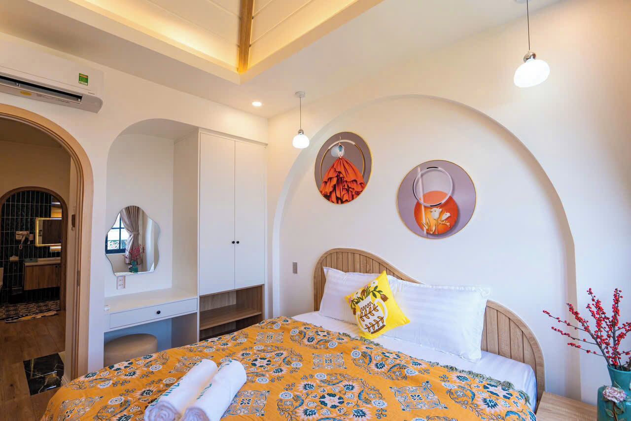 Une chambre d’hôtel comprenant un lit, une coiffeuse avec un miroir et un élément décoratif circulaire fixé au mur.