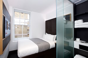 Une chambre d’hôtel moderne avec un grand lit, une paroi en verre et une vue sur la ville.