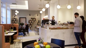 Un caffè moderno con un bancone centrale, zona salotto e pannelli decorativi a parete.