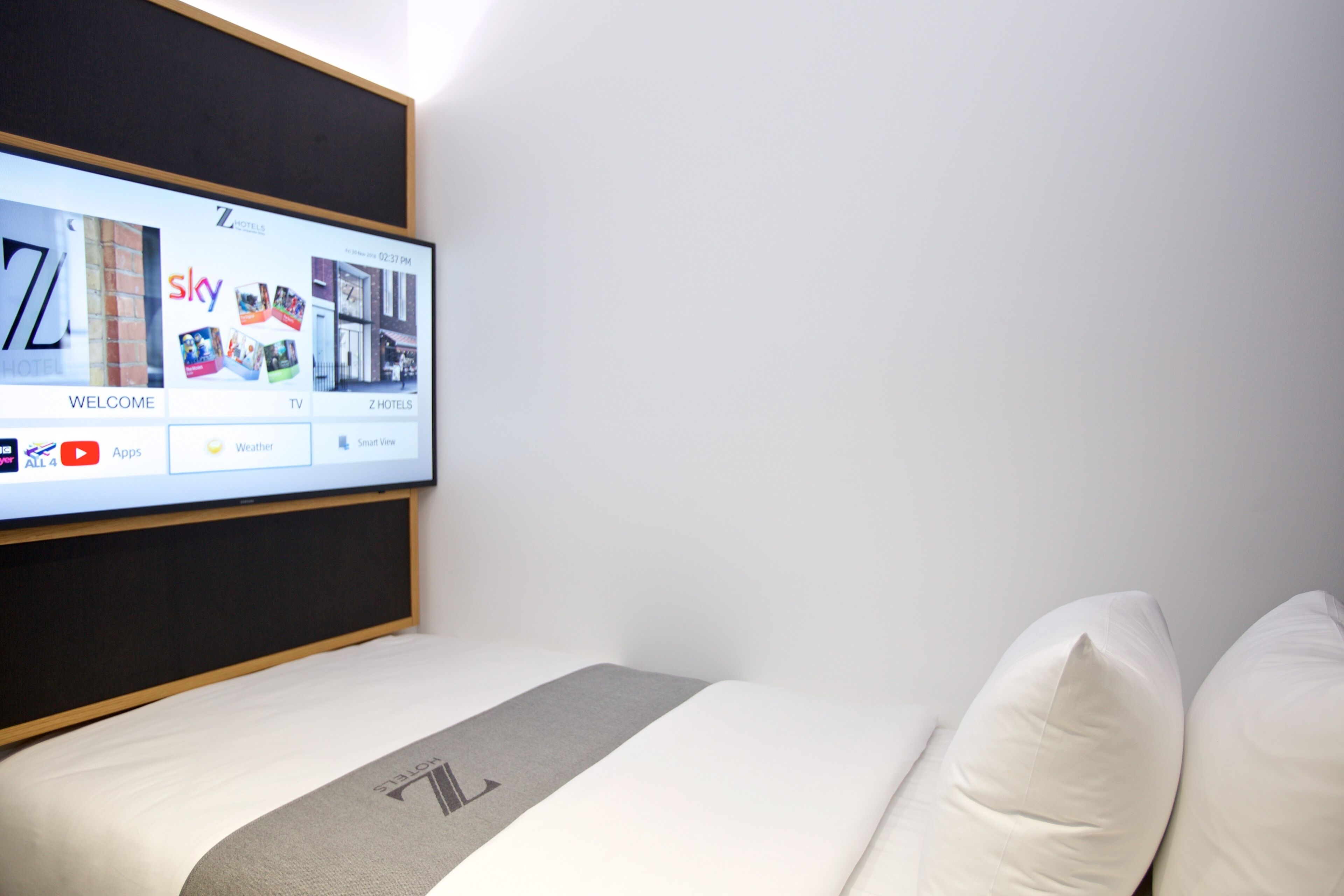 Ein Hotelzimmer mit einem großen Fernsehbildschirm, der eine Hotelwebseiten-Oberfläche zeigt.