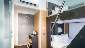 Una camera d'albergo compatta con un letto, una scrivania e un armadio.