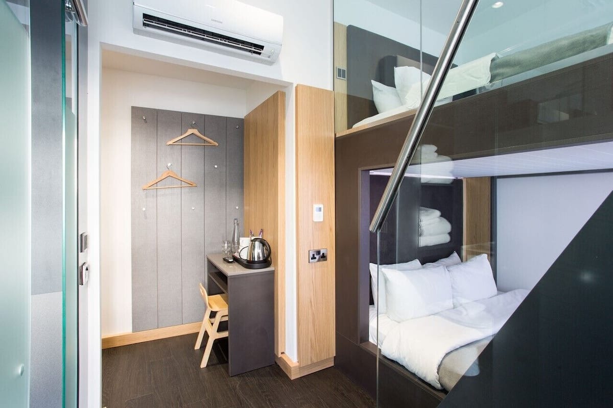 Una habitación de hotel compacta con cama, escritorio pequeño y armario.