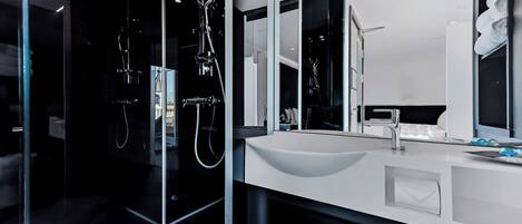 A modern bathroom with a glass-enclosed shower, a white sink, and a large mirror.