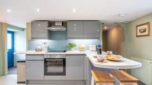 A modern kitchen with grey cabinets, a built-in oven, and a white countertop.