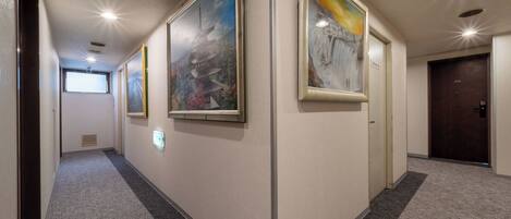 A hallway with framed artwork on the walls, a carpeted floor, and a door labeled "2014" at the end.