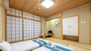 A traditional Japanese room with tatami flooring, two beds with blue and white bedding, a wooden desk, a television, and sliding doors. - PLAZA IN MIYAKOJIMA HOTEL (Osaka)