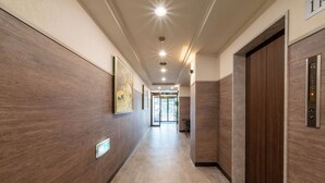 A modern hallway with wooden paneling, a tiled floor, and an elevator on the right.