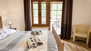 Un dormitorio con cama, una silla, una lámpara y vistas al exterior a través de una ventana.