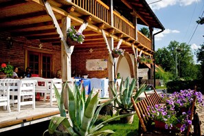 A wooden building with a balcony, outdoor seating, and potted plants. - Sasek Maly Pensjonat Jazdy Konne (Szczytno)