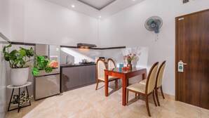 Une cuisine moderne avec un coin repas, comprenant une table et des chaises en bois, un réfrigérateur et une plante en pot.