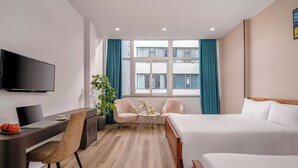 Une chambre d’hôtel avec un lit, un bureau, une chaise, une télévision et une fenêtre avec des rideaux.