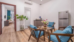 Une cuisine moderne équipée d’un réfrigérateur, un coin repas avec des chaises et une table en bois, et un couloir menant à une autre pièce.