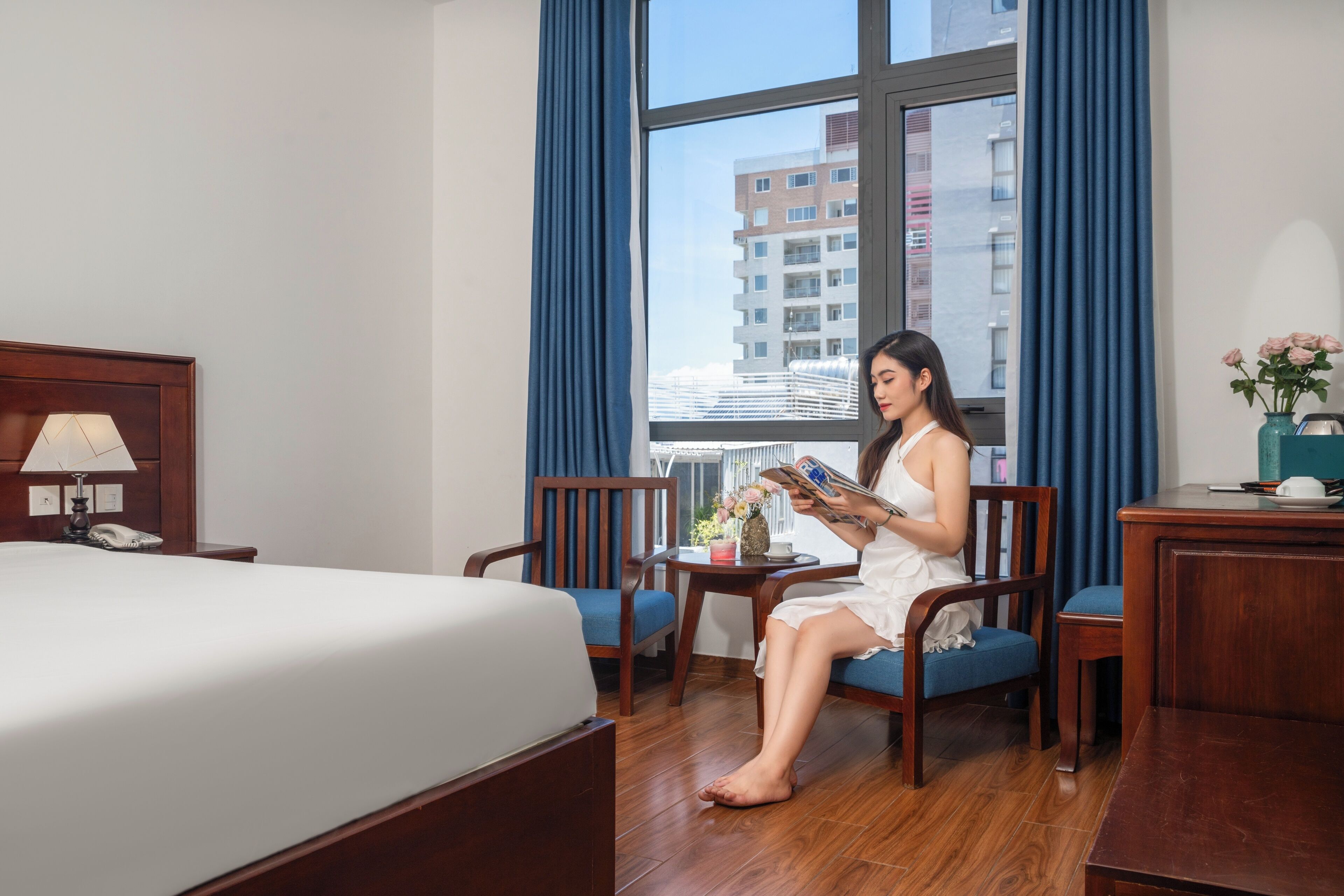 Habitación de hotel con una cama, un escritorio, una silla y vista a un edificio a través de una ventana.