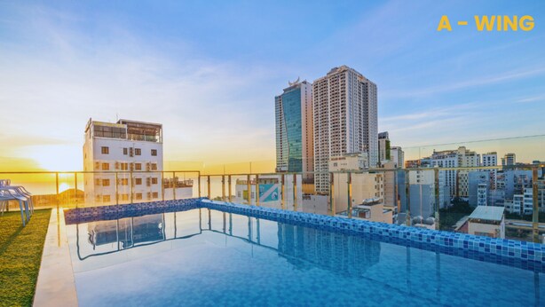 Une piscine sur le toit offrant une vue dégagée sur les immeubles environnants et un coucher de soleil en toile de fond.